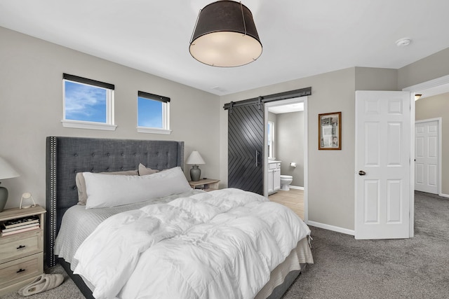 carpeted bedroom with ensuite bath, baseboards, and a barn door