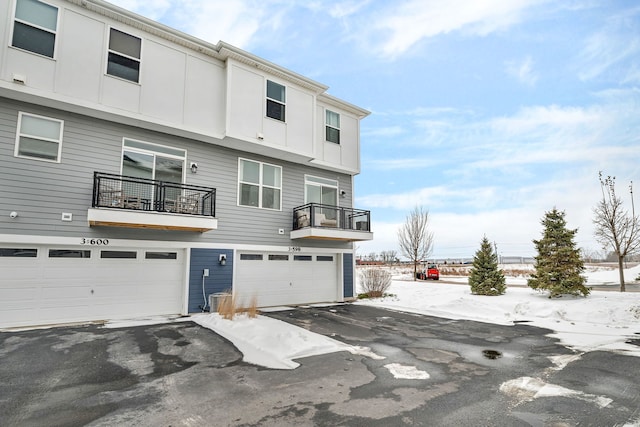 back of property with aphalt driveway and a garage