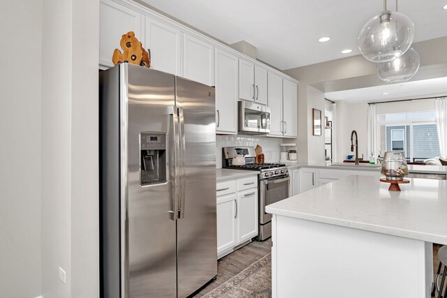 kitchen featuring a sink, dark wood finished floors, stainless steel appliances, a peninsula, and light countertops