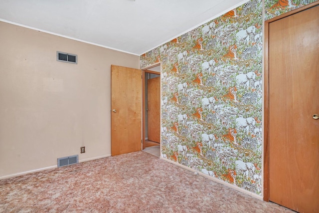 empty room featuring crown molding and carpet