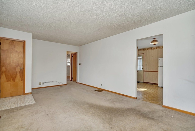 spare room with a textured ceiling and carpet flooring