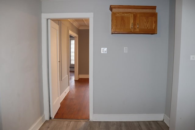 hallway with crown molding and light hardwood / wood-style flooring