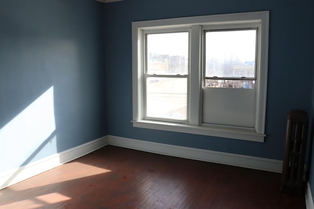 empty room with radiator and dark wood-type flooring