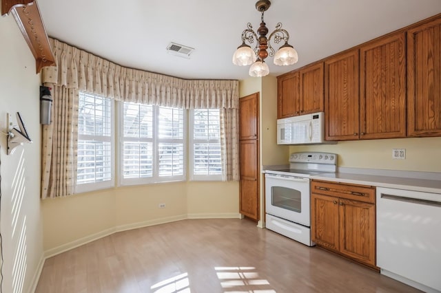 kitchen with white appliances, decorative light fixtures, a chandelier, and light hardwood / wood-style floors