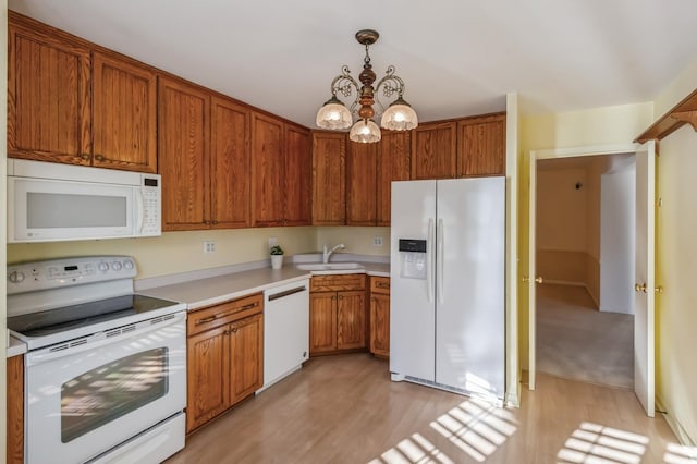 kitchen with sink, white appliances, light hardwood / wood-style flooring, decorative light fixtures, and a chandelier