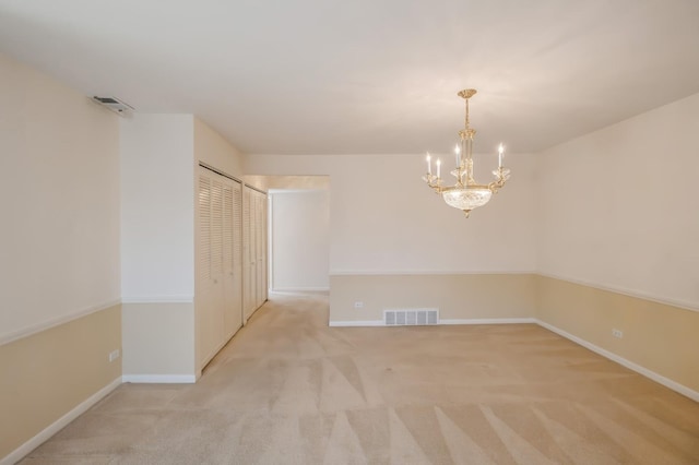 carpeted spare room with an inviting chandelier