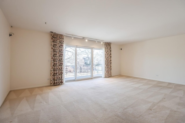 empty room featuring rail lighting and light carpet