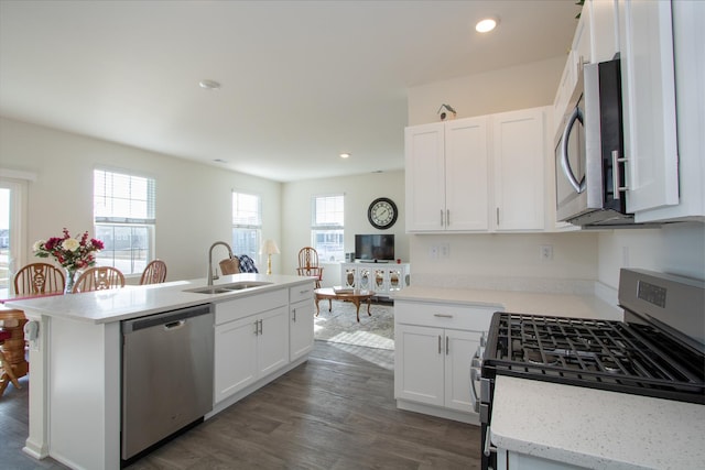 kitchen with stainless steel appliances, sink, white cabinets, and a kitchen island with sink