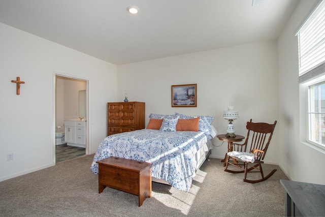 carpeted bedroom with multiple windows and connected bathroom