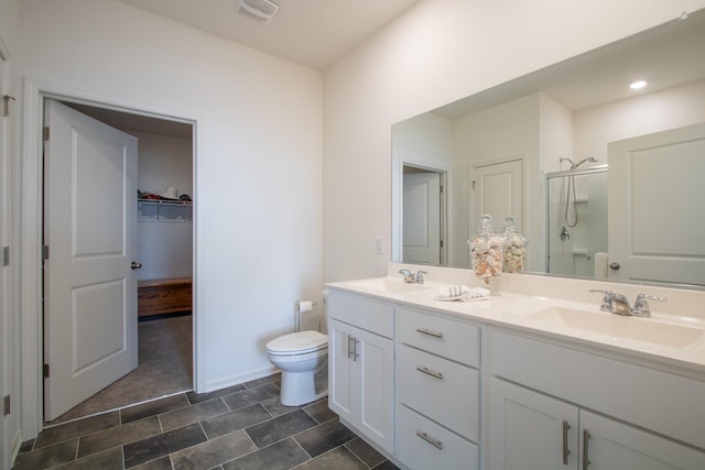 bathroom featuring vanity, a shower with door, and toilet