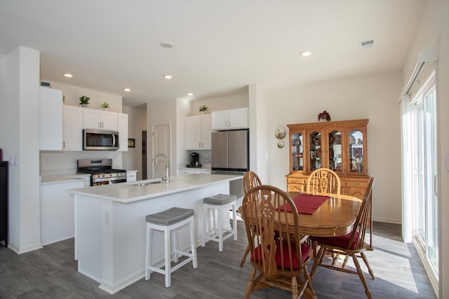 kitchen featuring sink, appliances with stainless steel finishes, white cabinetry, an island with sink, and dark hardwood / wood-style flooring