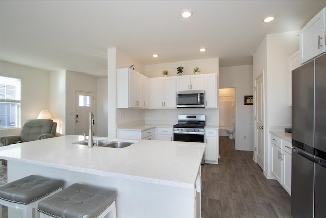 kitchen with sink, stainless steel appliances, dark hardwood / wood-style floors, white cabinets, and a center island with sink