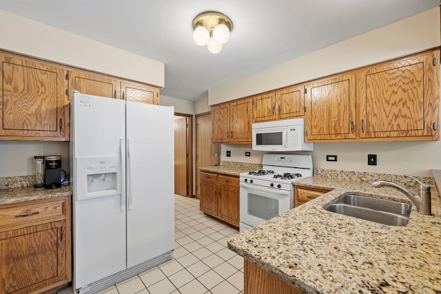 kitchen with sink, white appliances, light stone countertops, and light tile patterned flooring