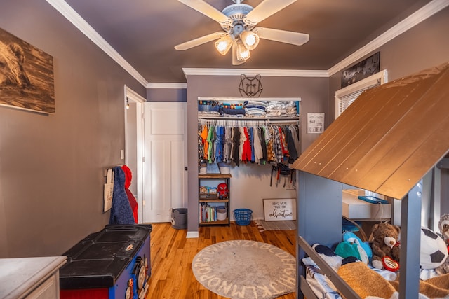 bedroom with ornamental molding, wood-type flooring, ceiling fan, and a closet