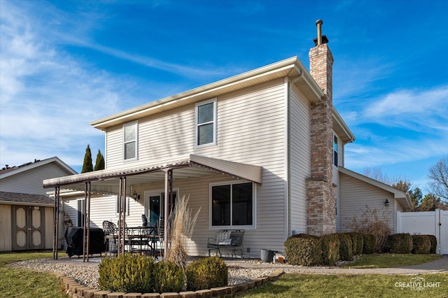 rear view of property with a storage shed and a patio