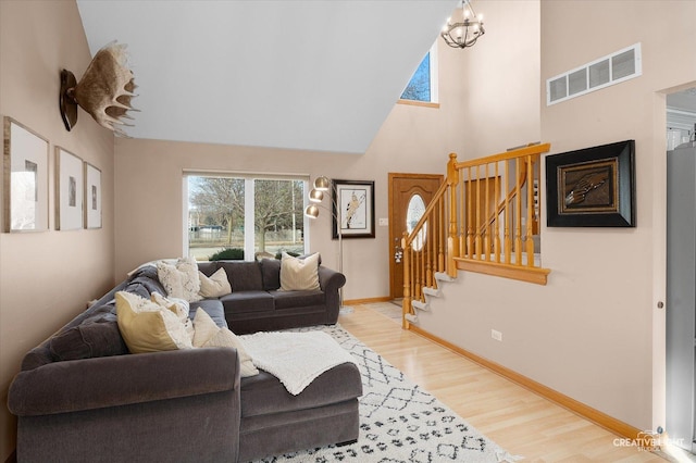 living room with a towering ceiling, a chandelier, and light hardwood / wood-style flooring