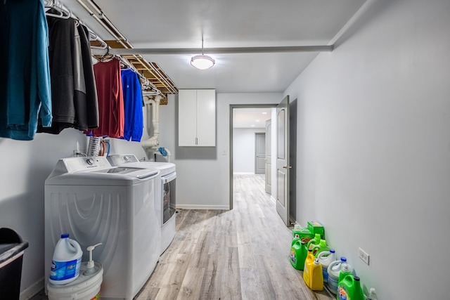 washroom with cabinets, washer and dryer, and light hardwood / wood-style floors