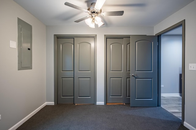 unfurnished bedroom with multiple closets, ceiling fan, electric panel, and dark carpet