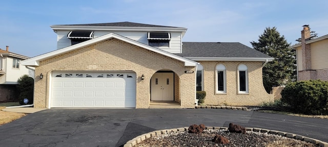 traditional home featuring brick siding, driveway, an attached garage, and roof with shingles