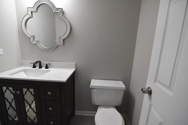 bathroom with baseboards, vanity, and toilet