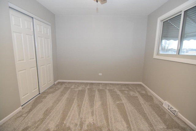 unfurnished bedroom featuring light carpet, a closet, visible vents, and baseboards