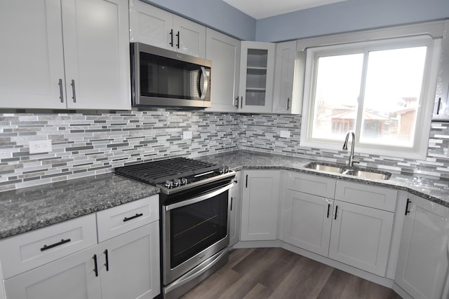 kitchen featuring sink, white cabinetry, appliances with stainless steel finishes, dark stone counters, and backsplash