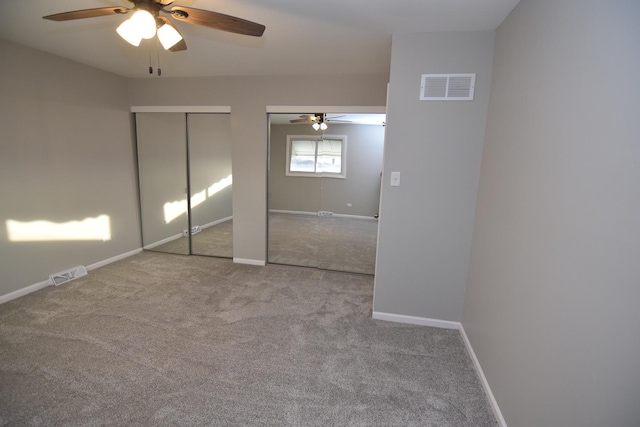 unfurnished bedroom with carpet floors, two closets, visible vents, and baseboards