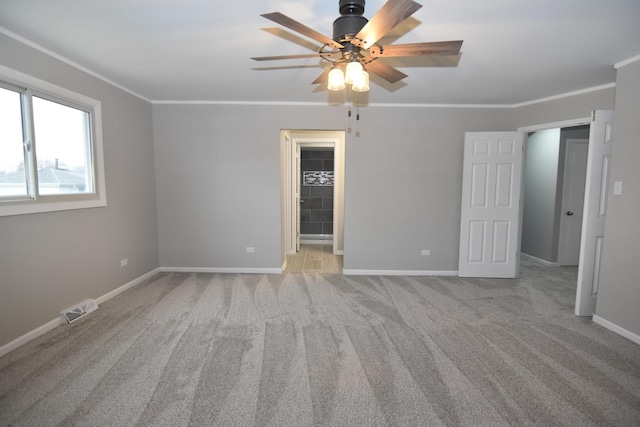 unfurnished room with baseboards, visible vents, crown molding, and light colored carpet