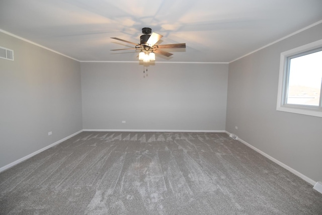 carpeted spare room with a ceiling fan, visible vents, baseboards, and crown molding