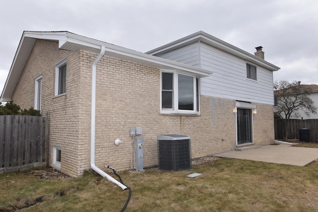 rear view of property with fence, central AC unit, a patio, and brick siding