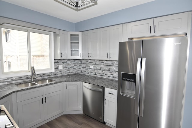 kitchen with tasteful backsplash, appliances with stainless steel finishes, glass insert cabinets, white cabinetry, and a sink