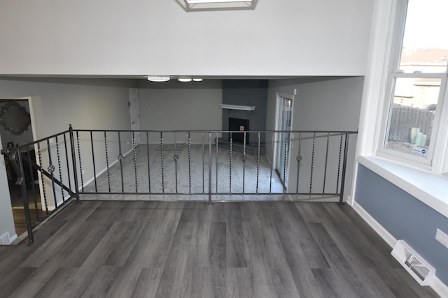 empty room featuring dark wood-style floors, visible vents, a fireplace, and baseboards