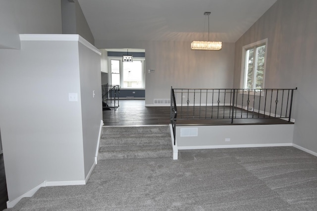 stairway with lofted ceiling, carpet floors, and an inviting chandelier