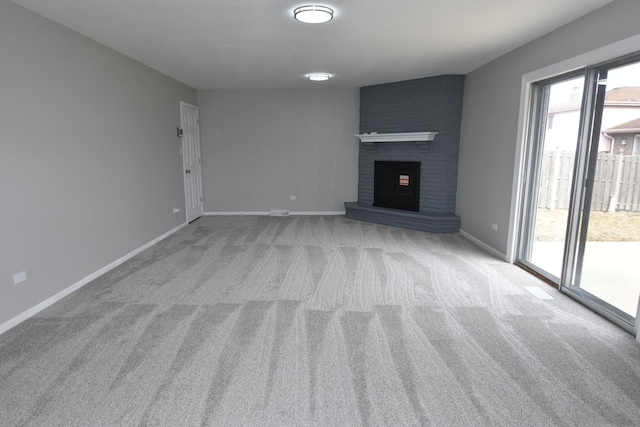 unfurnished living room featuring a brick fireplace, light carpet, and baseboards