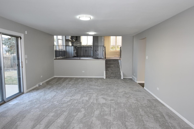 unfurnished living room featuring dark carpet and baseboards