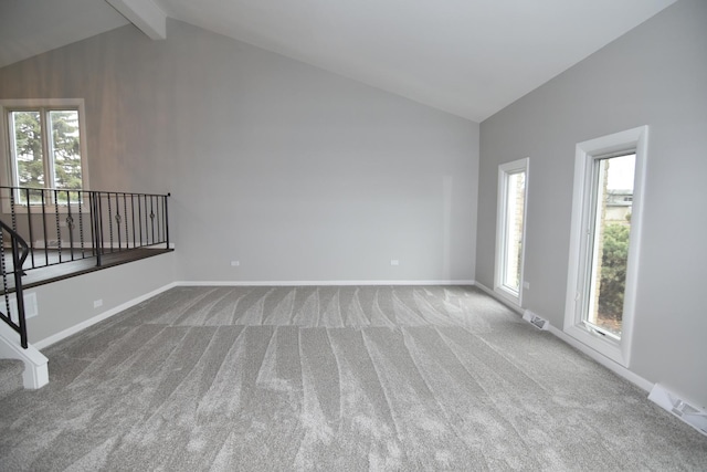 interior space with carpet floors, visible vents, lofted ceiling with beams, and baseboards