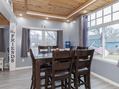 dining area with wood ceiling, a raised ceiling, and hardwood / wood-style floors