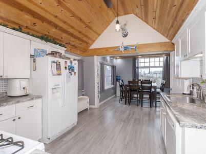 kitchen with sink, wood ceiling, light hardwood / wood-style flooring, white fridge with ice dispenser, and white cabinets