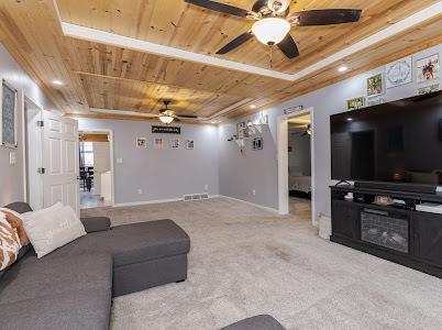 living room with wooden ceiling, ceiling fan, and carpet