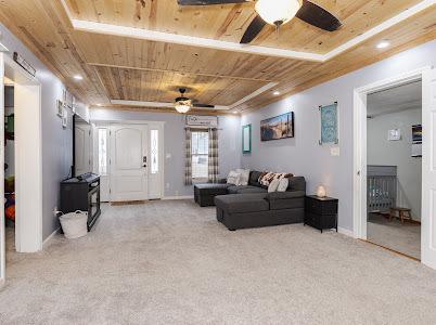 living room with light carpet, wood ceiling, and ceiling fan