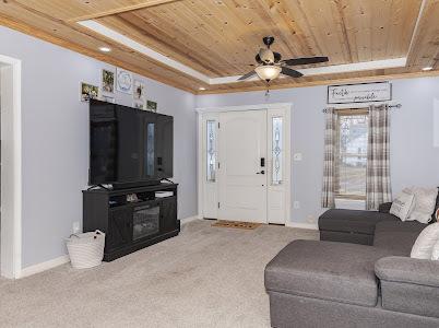 carpeted living room featuring ceiling fan, a tray ceiling, and wooden ceiling