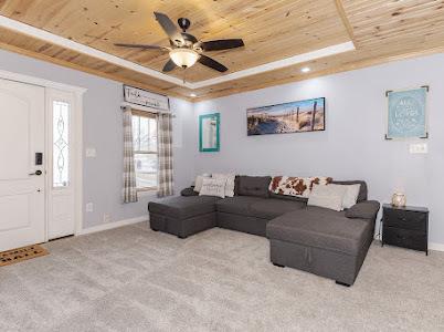 carpeted living room featuring ceiling fan, a tray ceiling, and wooden ceiling