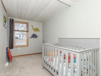 bedroom with vaulted ceiling, light colored carpet, and a nursery area