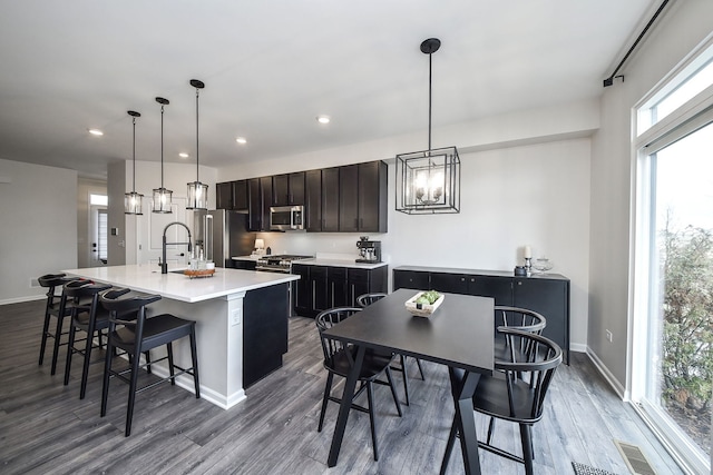 kitchen featuring pendant lighting, an island with sink, high quality appliances, and a breakfast bar