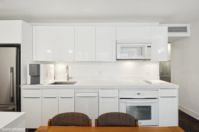 kitchen featuring sink, white appliances, and white cabinets