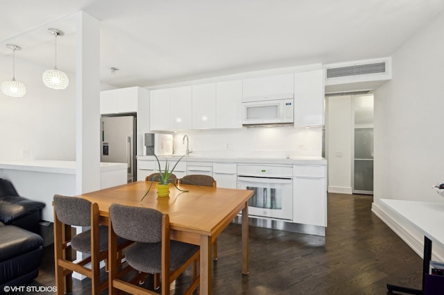 kitchen featuring sink, white appliances, hanging light fixtures, dark hardwood / wood-style floors, and white cabinets