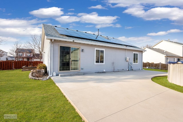 rear view of property featuring a yard, a patio area, and solar panels