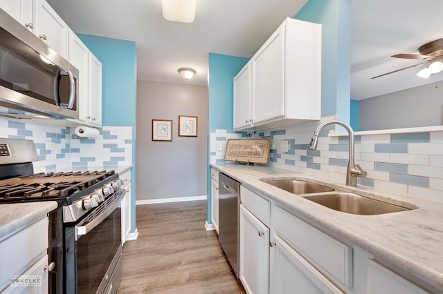 kitchen with sink, ceiling fan, appliances with stainless steel finishes, white cabinets, and light wood-type flooring