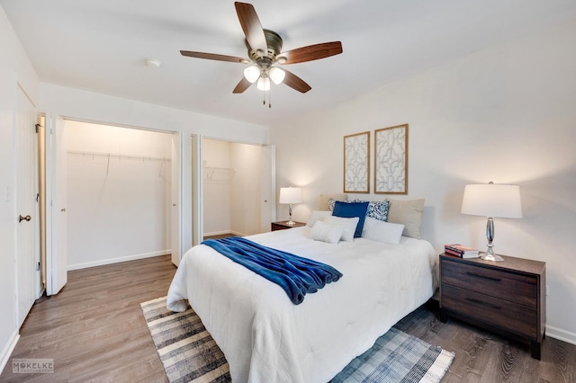 bedroom featuring hardwood / wood-style floors, multiple closets, and ceiling fan