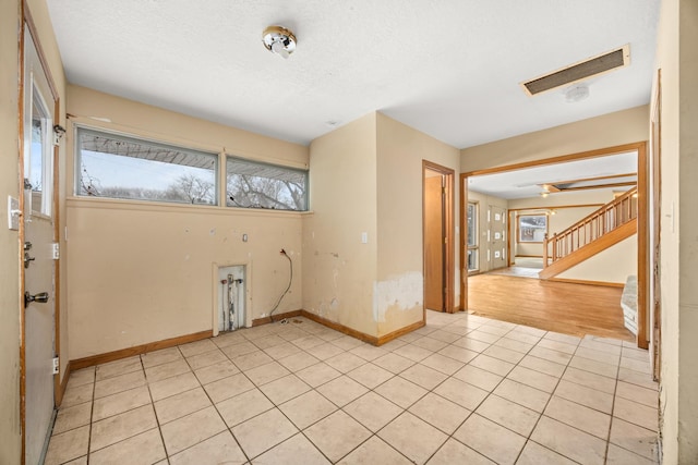 spare room featuring light tile patterned floors, plenty of natural light, and a textured ceiling